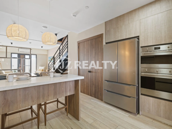 Porta al Sole Unit 11 kitchen view showcasing the built-in stainless steel double oven, large refrigerator, and light wood-grain cabinetry.