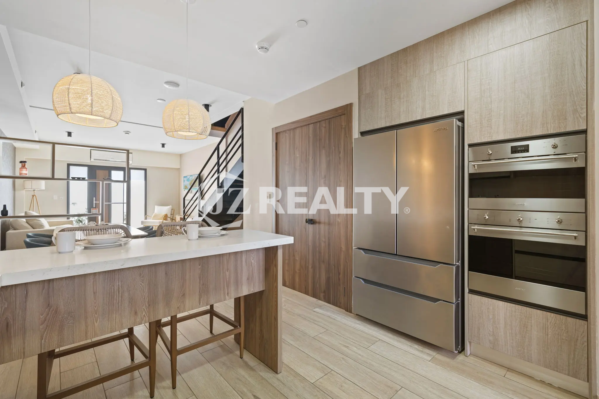 Porta al Sole Unit 11 kitchen view showcasing the built-in stainless steel double oven, large refrigerator, and light wood-grain cabinetry.
