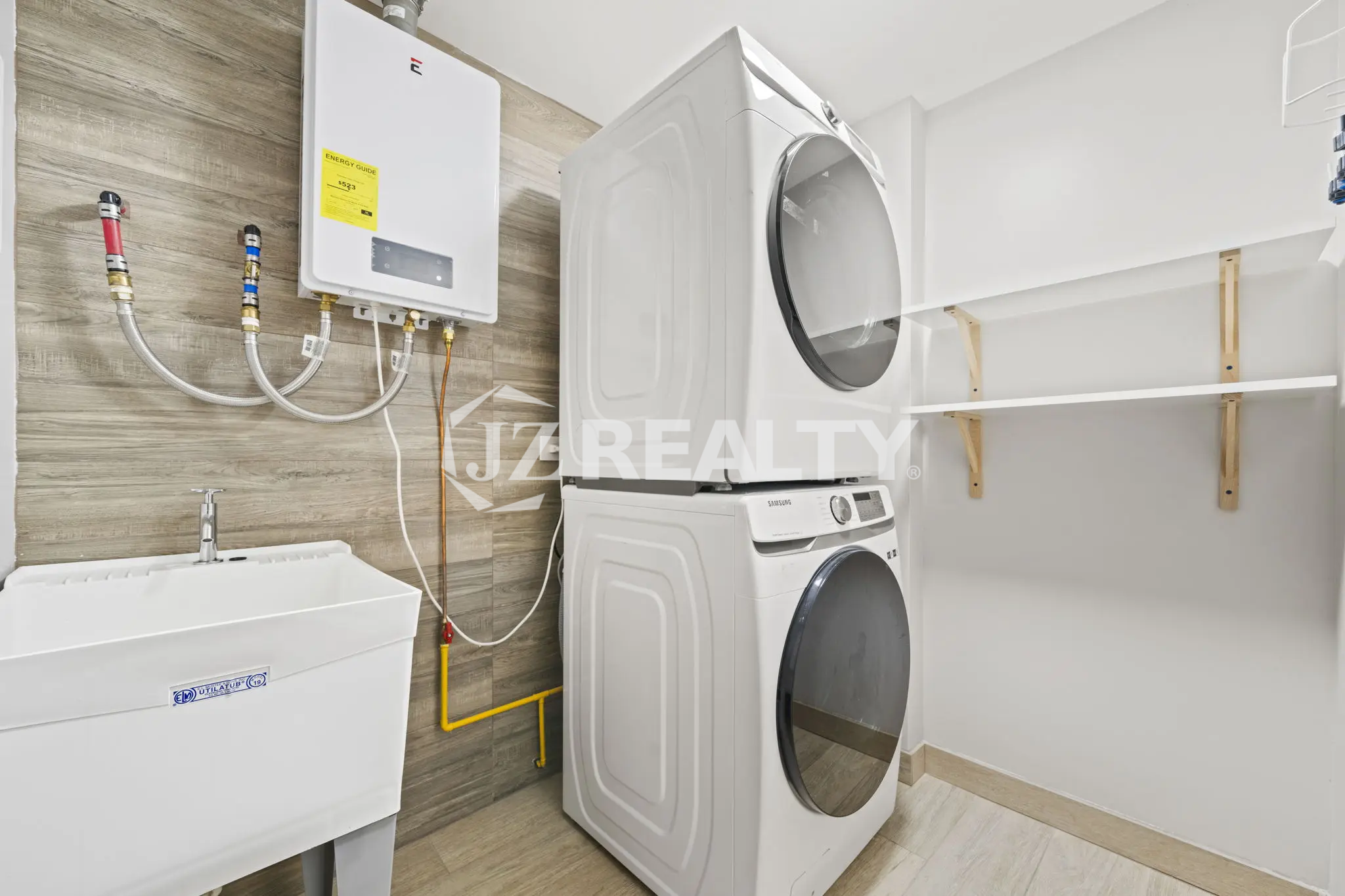 Porta al Sole Unit 11 modern laundry room with stacked washer and dryer, white utility sink, and wall-mounted tankless water heater.