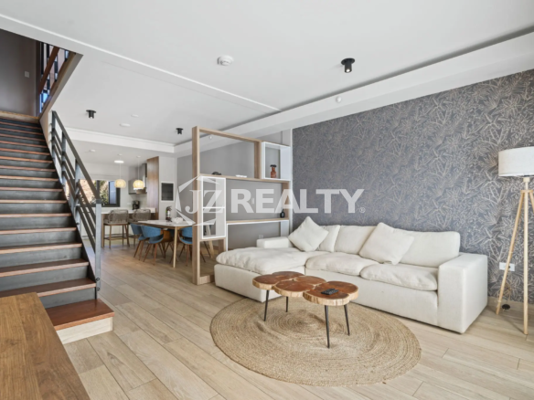 Porta al Sole Unit 11 living area showing the white sectional sofa against a dark patterned accent wall and the open wood and metal staircase.