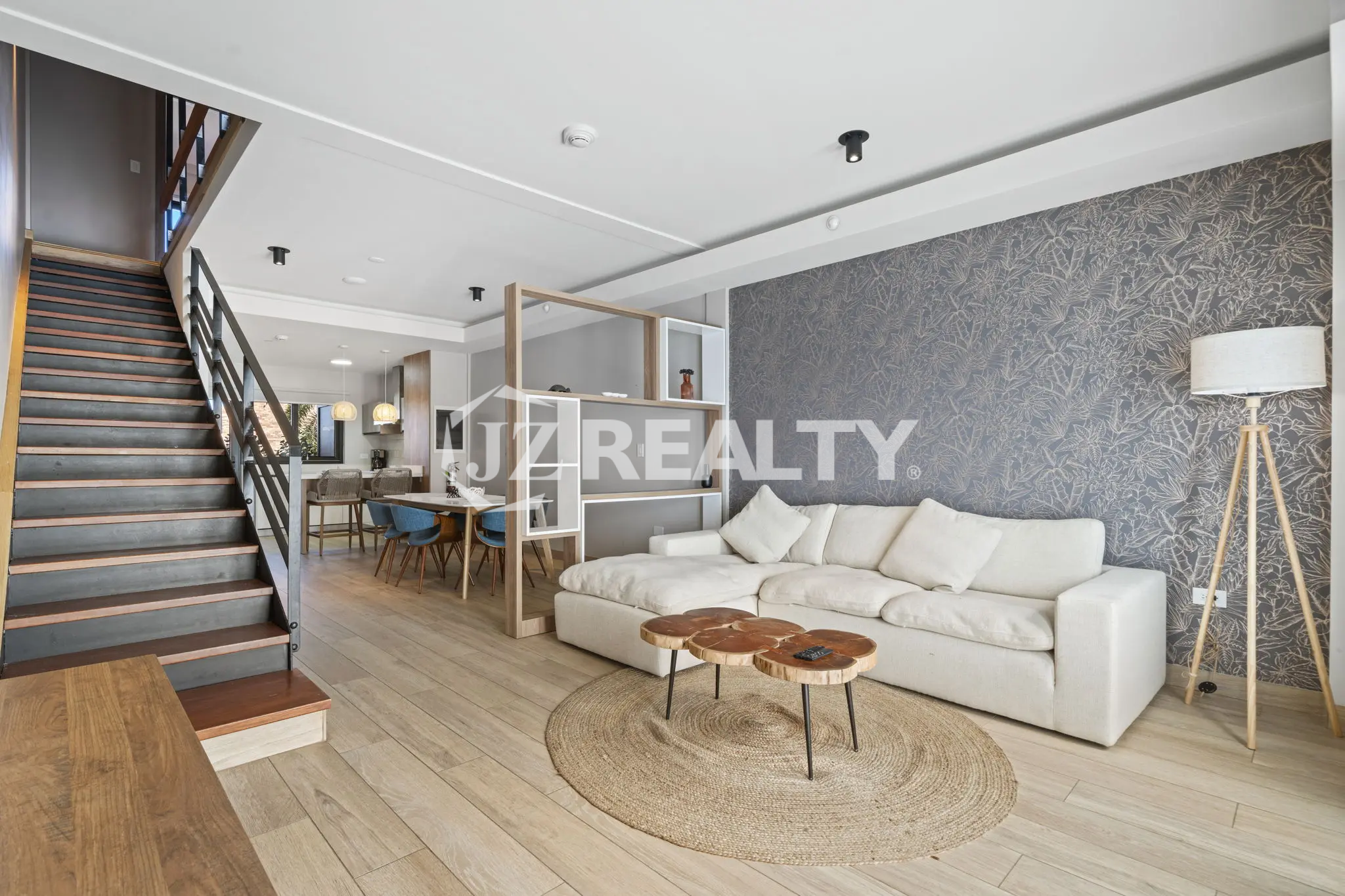 Porta al Sole Unit 11 living area showing the white sectional sofa against a dark patterned accent wall and the open wood and metal staircase.