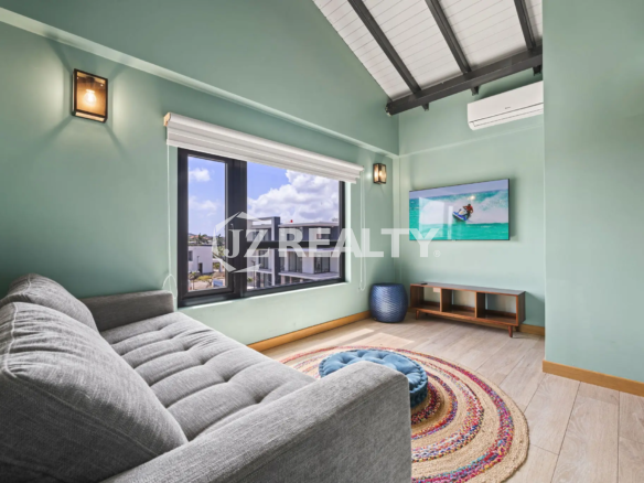 Porta al Sole Unit 11 bright living area with mint green walls, a grey sofa/daybed, wall-mounted TV, and an air conditioning unit.
