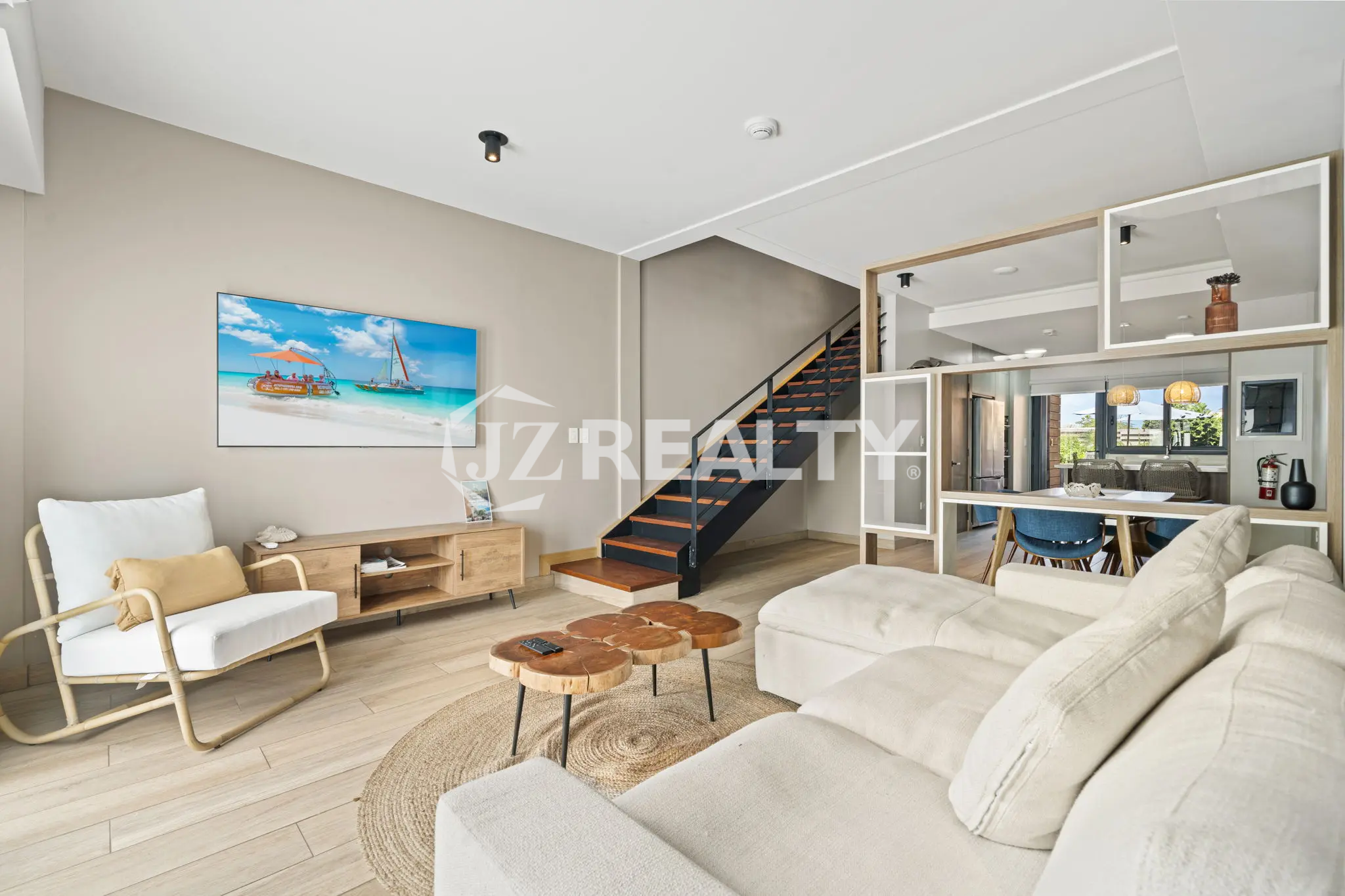Porta al Sole Unit 11 bright living room with a large white sectional sofa, wood media console, natural fiber rug, and view of the interior staircase.