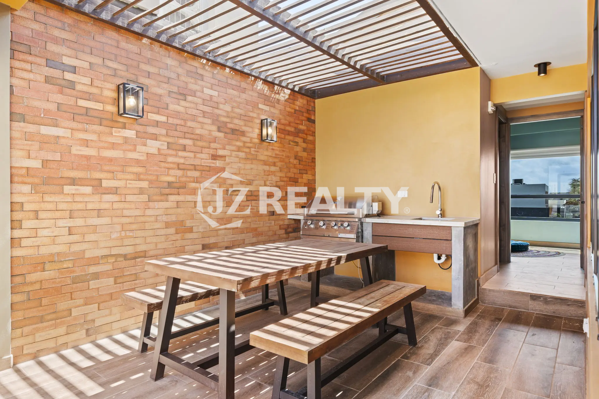 Porta al Sole Unit 11 outdoor covered dining and grilling area with a wooden picnic table, built-in stainless steel BBQ grill, and sink under a slatted pergola.