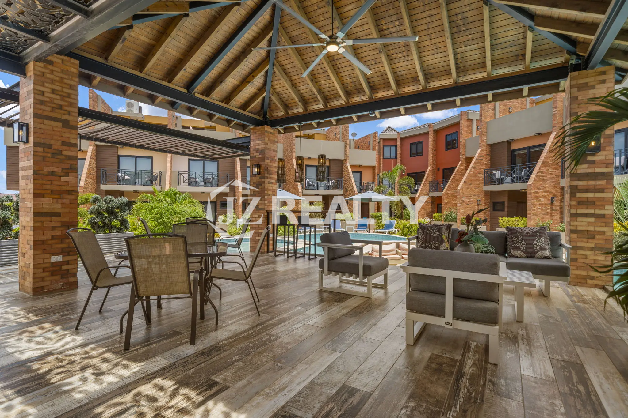 Porta al Sole Unit 11 covered community area next to the pool featuring a high wooden roof, ceiling fan, and various outdoor seating arrangements.