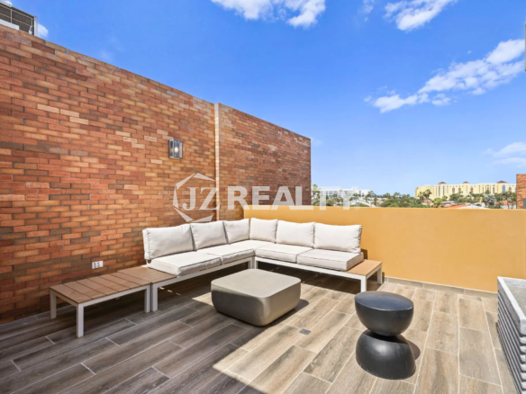 Porta al Sole Unit 11 modern rooftop terrace with a large white L-shaped sectional sofa, grey coffee table, and wood-style flooring.