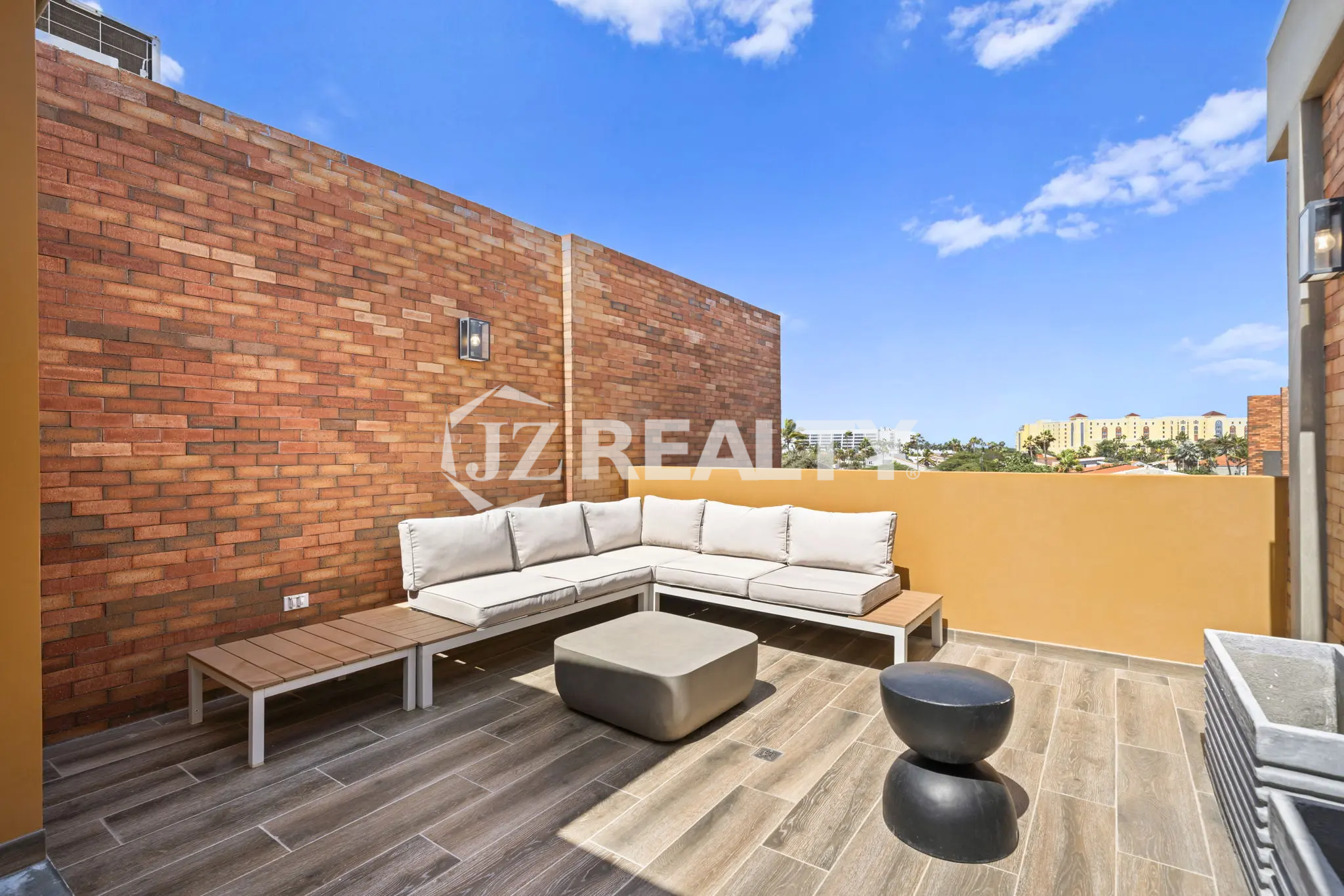 Porta al Sole Unit 11 modern rooftop terrace with a large white L-shaped sectional sofa, grey coffee table, and wood-style flooring.