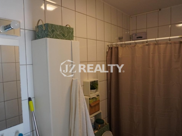 Tiled bathroom with shower curtain and storage shelves in an Aruba apartment.