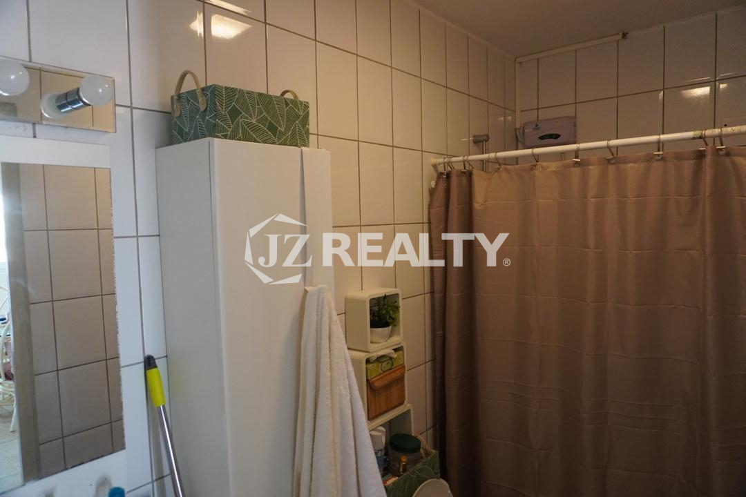 Tiled bathroom with shower curtain and storage shelves in an Aruba apartment.