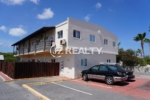 Exterior of two-story apartment building with balconies and parking in Aruba.