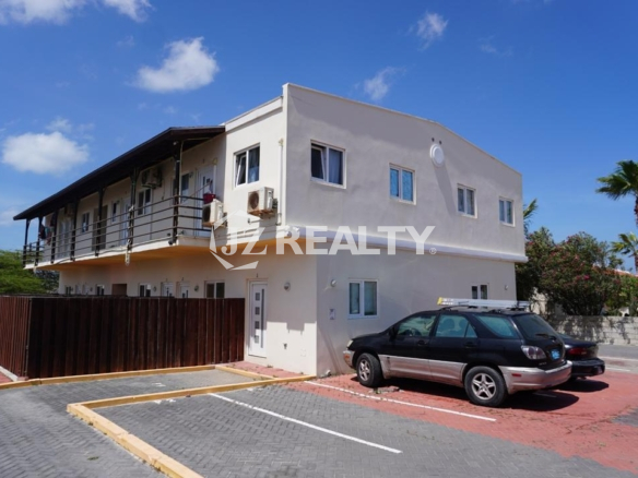Exterior of two-story apartment building with balconies and parking in Aruba.