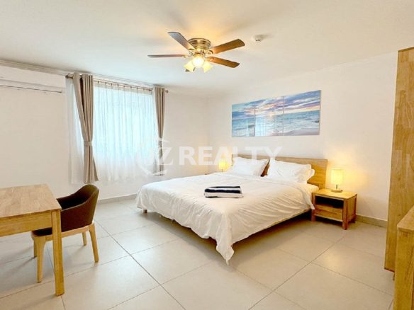 Bedroom with a king bed, air conditioner, and bright window.