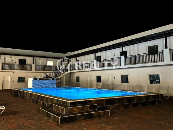 Night view of the courtyard pool and surrounding two-story buildings.