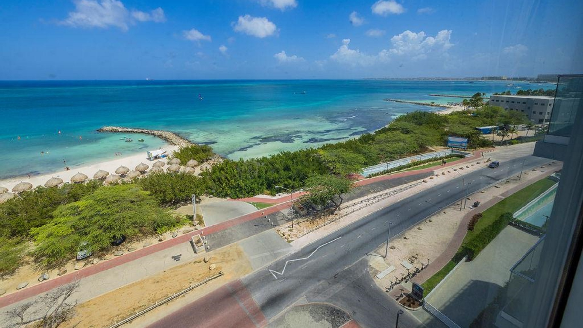 Aerial view near Penthouse PHA at The Reef Residences showing road and beach in Eagle Beach Aruba