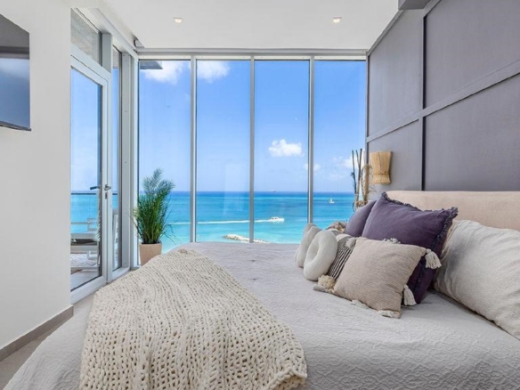 Bedroom in Penthouse PHA at The Reef Residences featuring large windows and direct ocean views in Eagle Beach Aruba