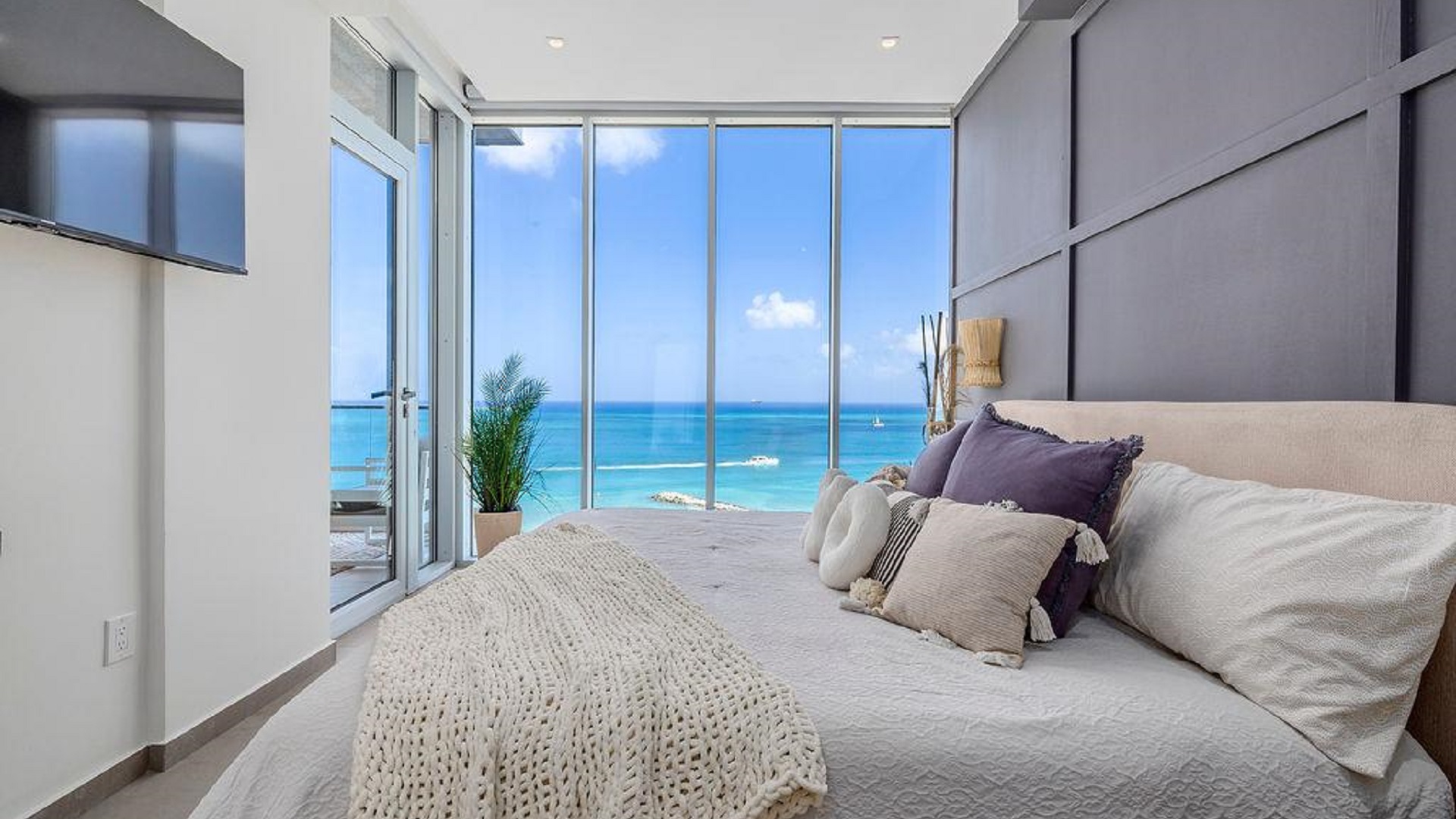 Bedroom in Penthouse PHA at The Reef Residences featuring large windows and direct ocean views in Eagle Beach Aruba