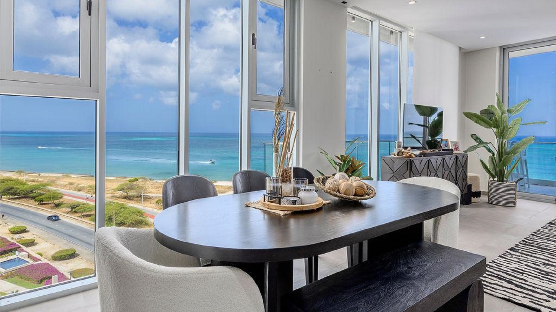 Dining area in Reef Residences PHA penthouse beside large ocean view windows in Eagle Beach Aruba