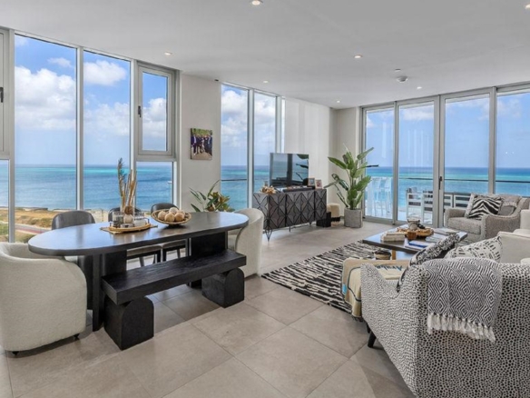 Open living and dining area of Reef Residences PHA penthouse with ocean views through floor-to-ceiling windows in Eagle Beach Aruba