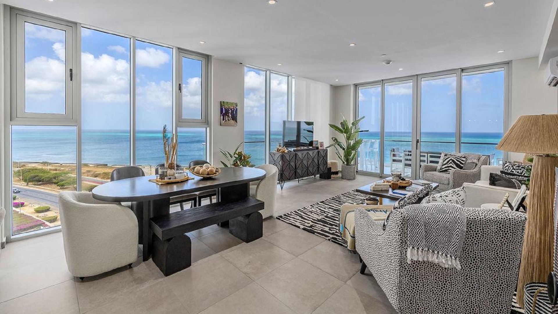 Open living and dining area of Reef Residences PHA penthouse with ocean views through floor-to-ceiling windows in Eagle Beach Aruba