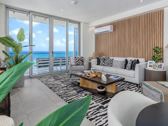 Stylish living room in Reef Residences PHA penthouse facing the ocean with large glass doors in Eagle Beach Aruba