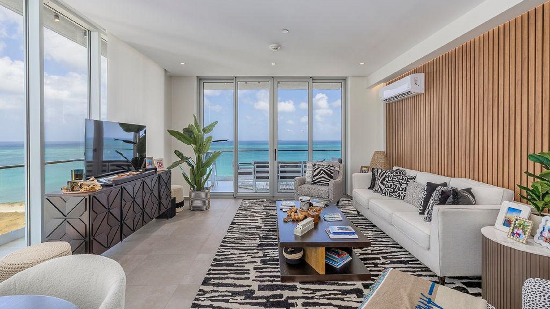 Living room in Reef Residences PHA penthouse with large windows showcasing oceanfront views in Eagle Beach Aruba