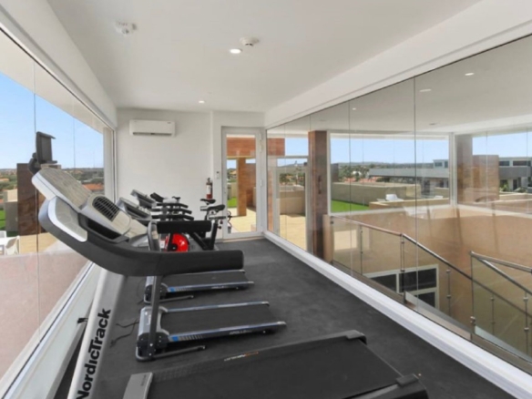 Fitness room at the 2-Bedroom Oasis at Aracari in Aruba with treadmills, exercise equipment, and large glass windows.