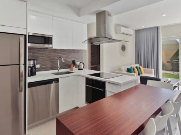 Open kitchen and dining area at the 2-Bedroom Oasis at Aracari in Aruba with stainless steel appliances, dining table, and breakfast bar.