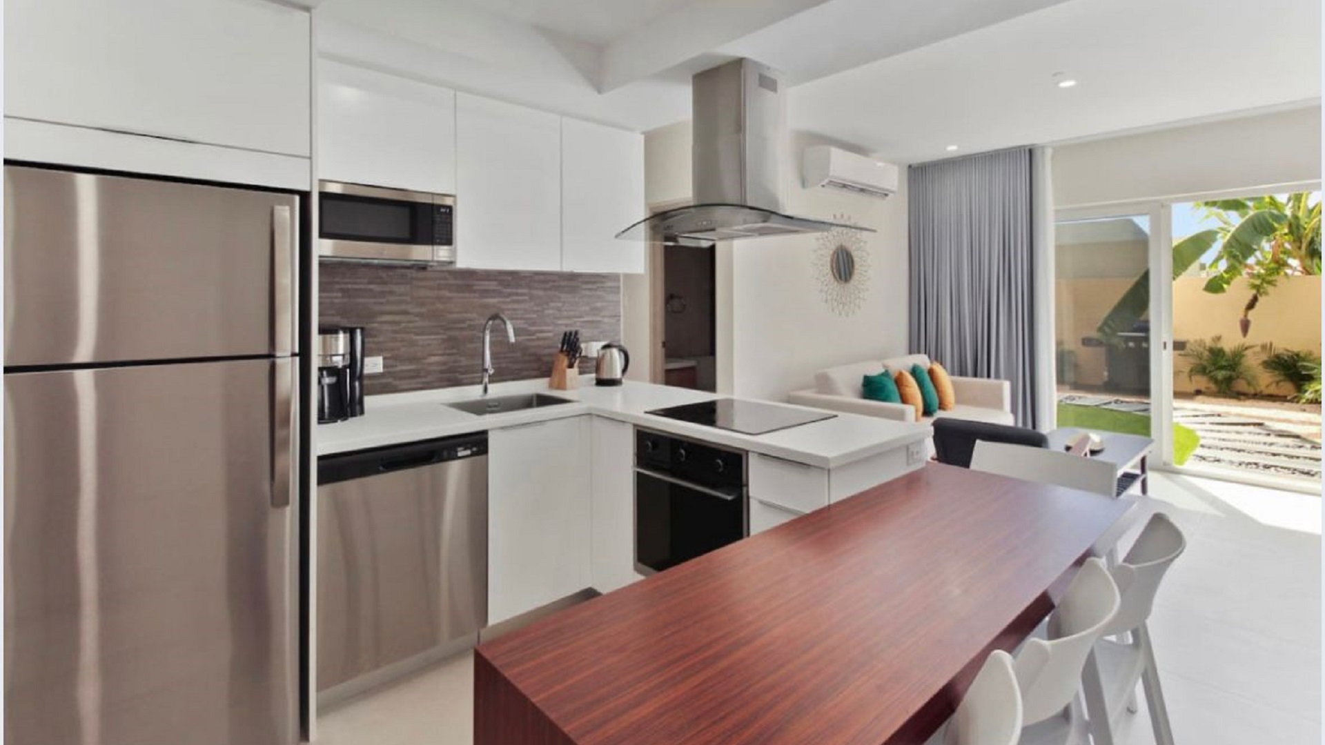 Open kitchen and dining area at the 2-Bedroom Oasis at Aracari in Aruba with stainless steel appliances, dining table, and breakfast bar.