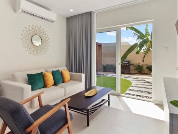 Living room at the 2-Bedroom Oasis at Aracari in Aruba with modern seating, sliding glass doors, and garden view