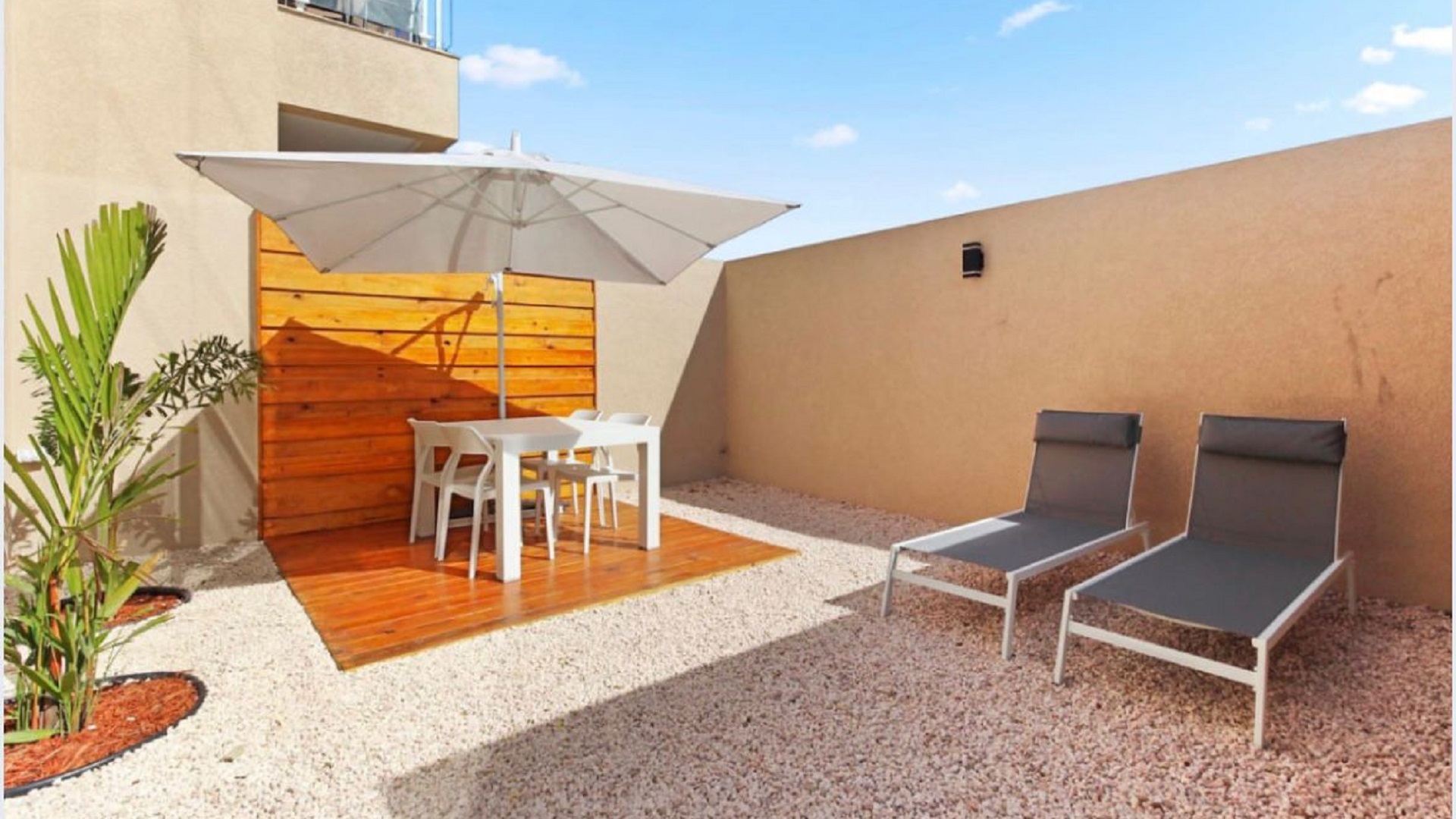 Outdoor lounge space at the 2-Bedroom Oasis at Aracari in Aruba with umbrella-covered dining table and sun loungers