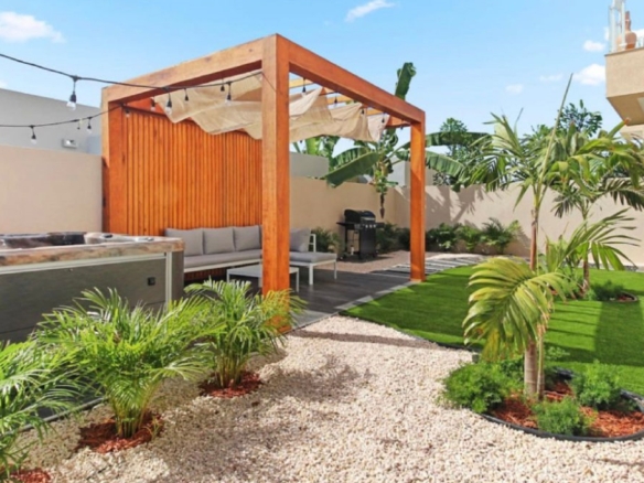 Outdoor patio at the 2-Bedroom Oasis at Aracari in Aruba with pergola seating area, landscaped garden, and hot tub