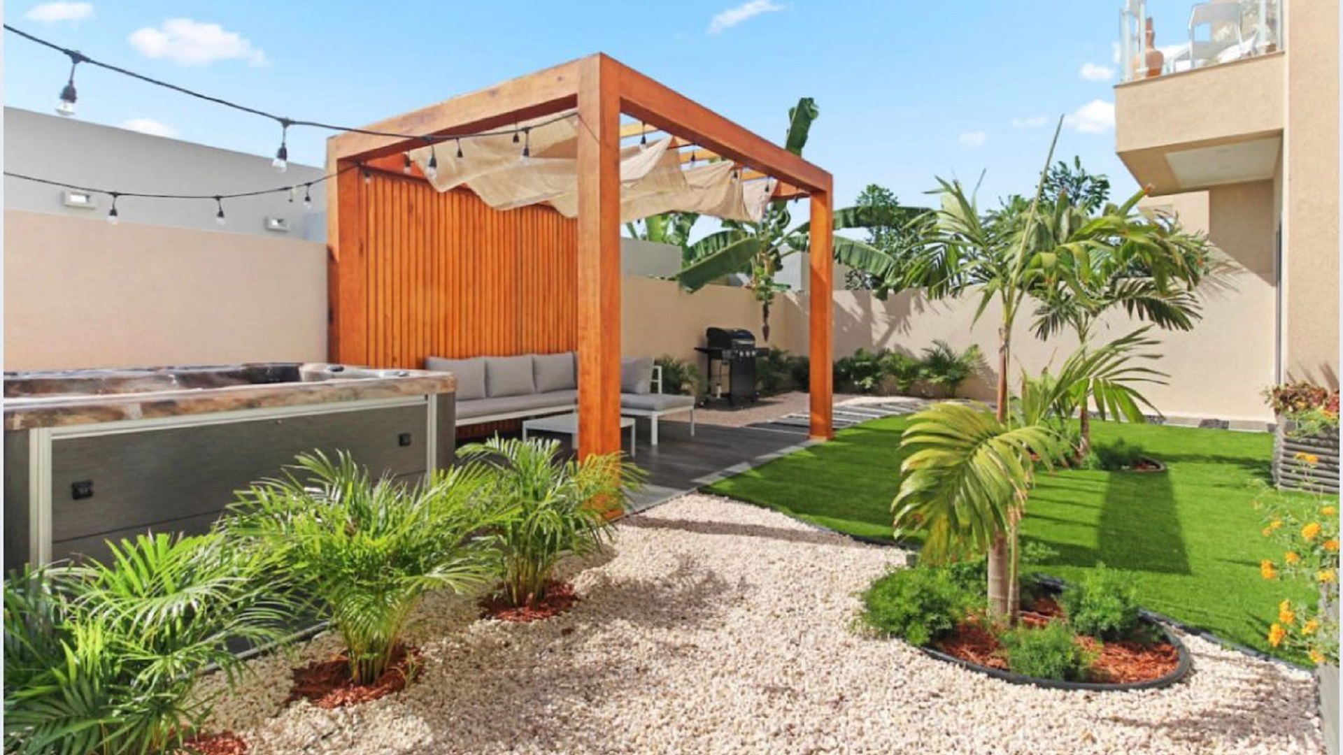 Outdoor patio at the 2-Bedroom Oasis at Aracari in Aruba with pergola seating area, landscaped garden, and hot tub