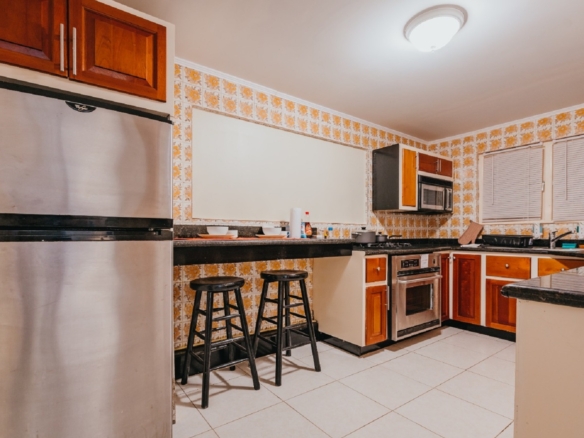 Kitchen inside the 7 studio apartments in Aruba with stainless steel refrigerator, bar seating, tiled flooring, and wood cabinetry