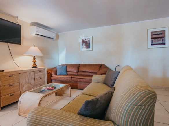 Alternate view of the living room in the 7 studio apartments in Aruba showing sofas, coffee table, TV, and open layout.