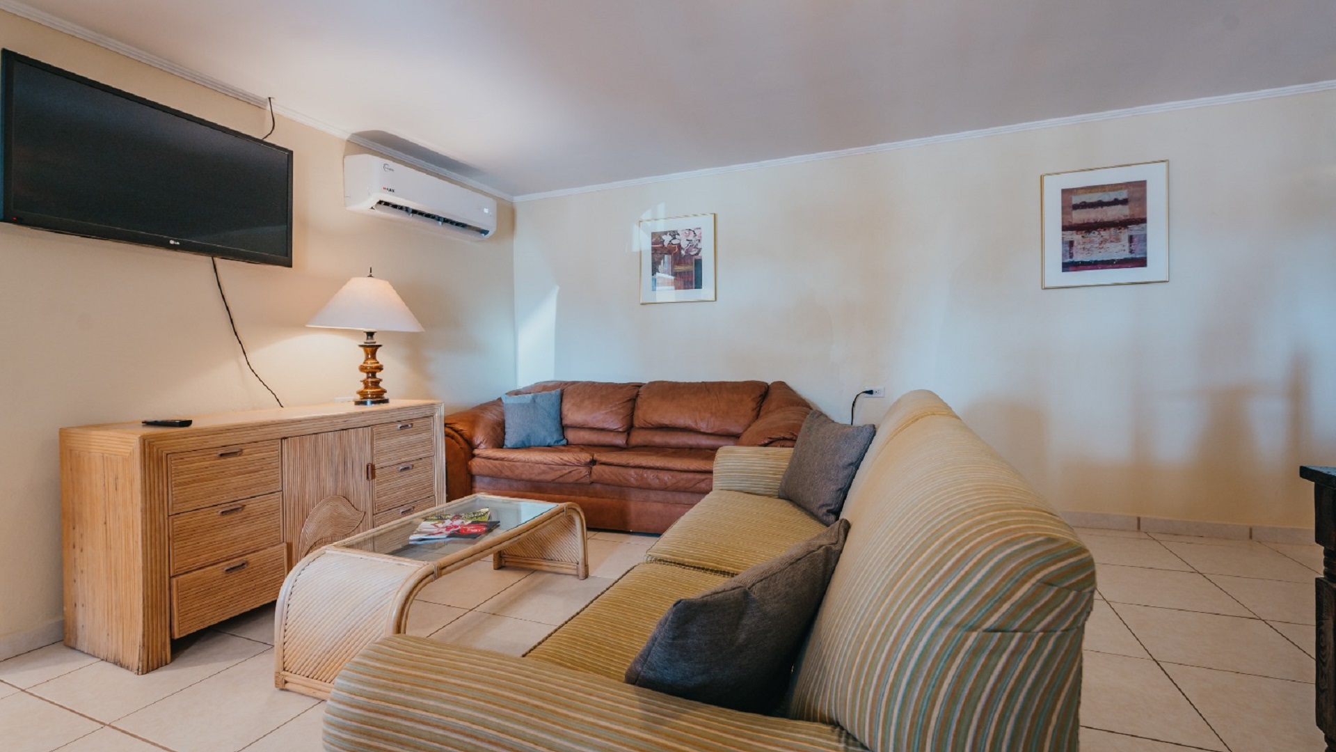 Alternate view of the living room in the 7 studio apartments in Aruba showing sofas, coffee table, TV, and open layout.