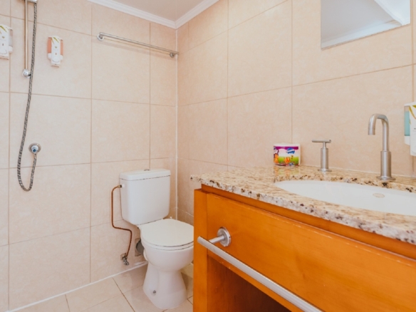 Modern bathroom in the 7 studio apartments in Aruba with tiled walls, vanity sink, toilet, and walk-in shower.