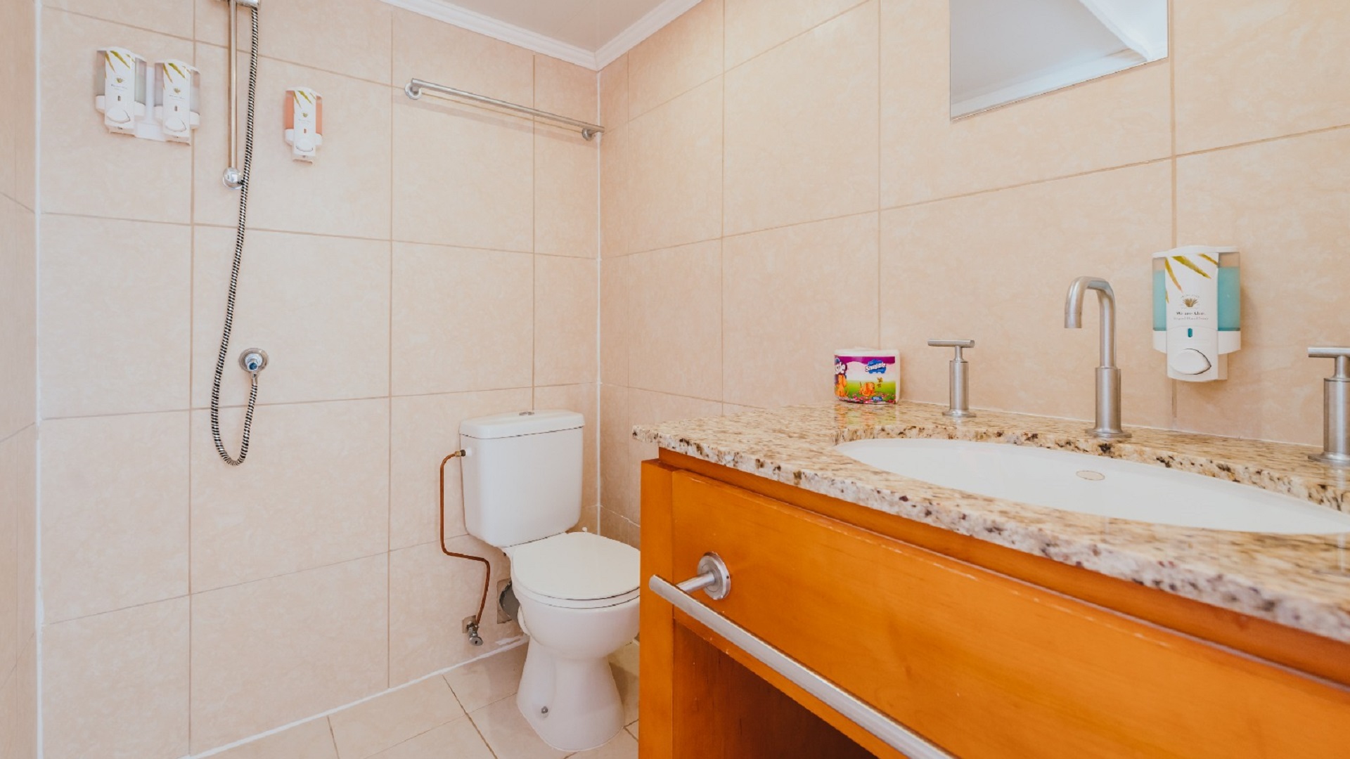 Modern bathroom in the 7 studio apartments in Aruba with tiled walls, vanity sink, toilet, and walk-in shower.