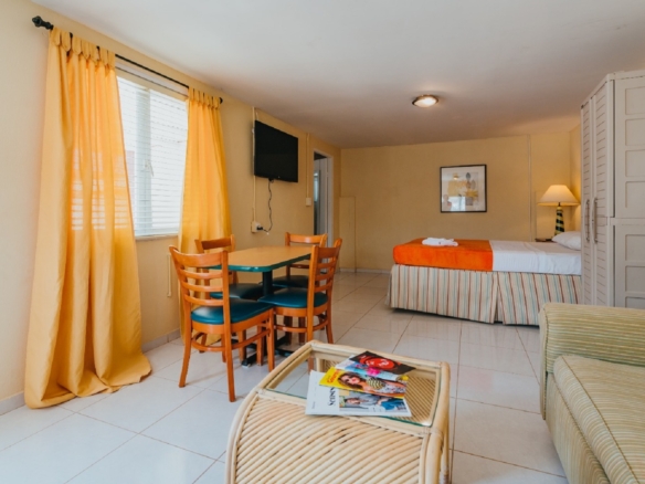 Interior of a studio apartment in Aruba with a bed, dining table, seating area, and tiled flooring