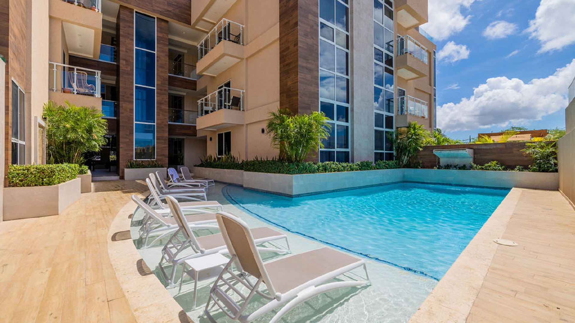 Swimming pool area at Aracari Phase II condominium complex in Aruba with lounge chairs and landscaped surroundings
