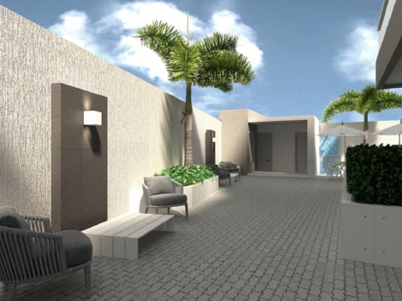 Landscaped courtyard walkway with seating and palm trees at Aracari Phase II condominiums in Aruba.