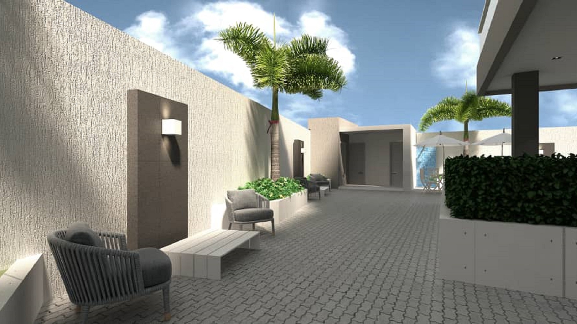 Landscaped courtyard walkway with seating and palm trees at Aracari Phase II condominiums in Aruba.