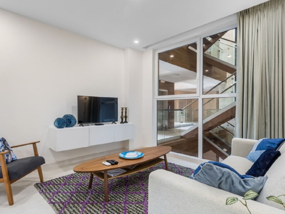 Living room interior at Aracari Phase II Unit 13 in Aruba with sofa seating and large windows