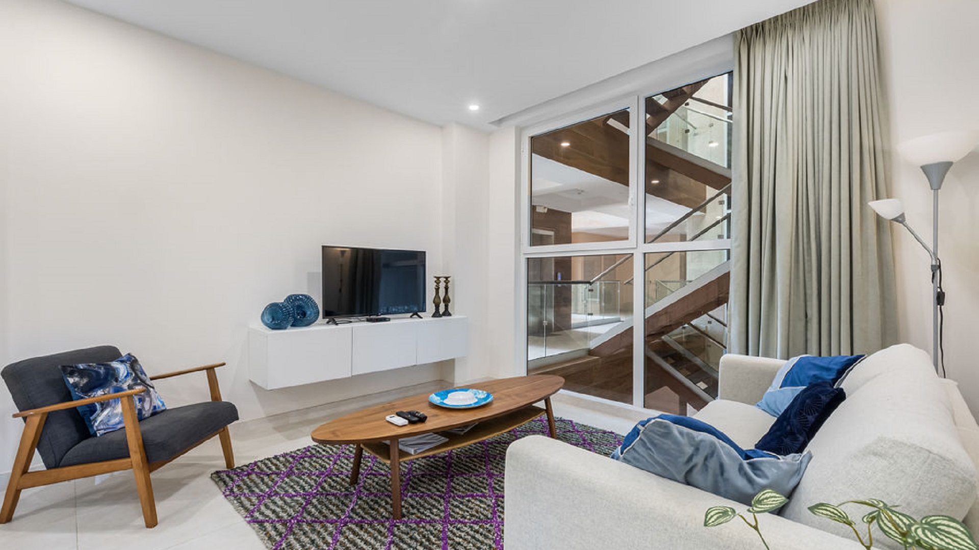 Living room interior at Aracari Phase II Unit 13 in Aruba with sofa seating and large windows