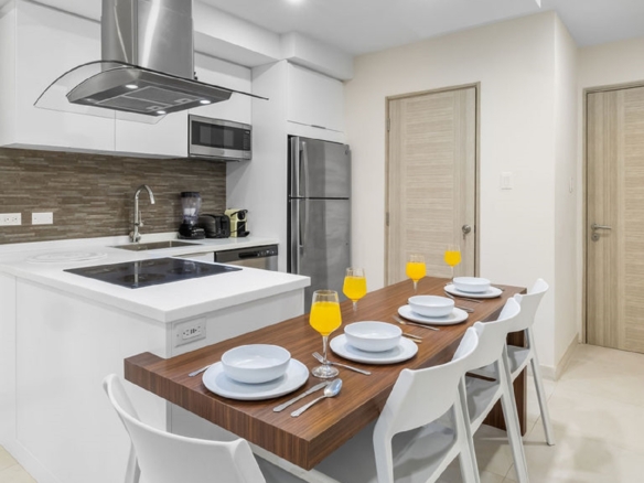 Modern kitchen inside Aracari Phase II Unit 13 condo in Aruba with white cabinetry and dining table