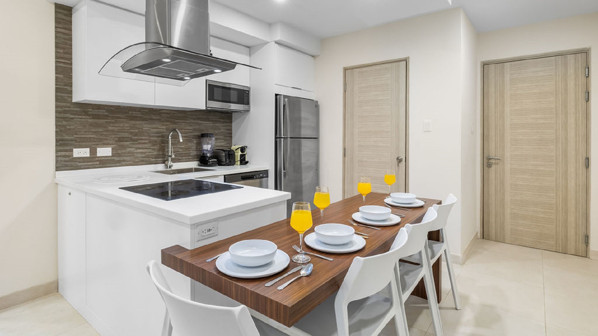 Modern kitchen inside Aracari Phase II Unit 13 condo in Aruba with white cabinetry and dining table