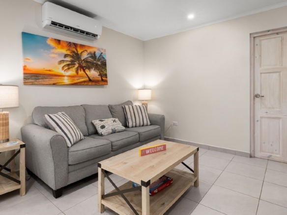 Living room inside the Summerside 2-bedroom condo in Rooi Santo, Aruba with sofa seating and wall-mounted television.
