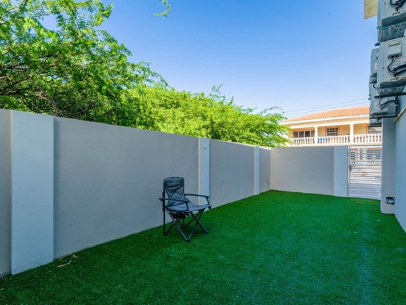 outdoor yard area at the Summerside 2-bedroom condo in Rooi Santo, Aruba with artificial grass and enclosed walls