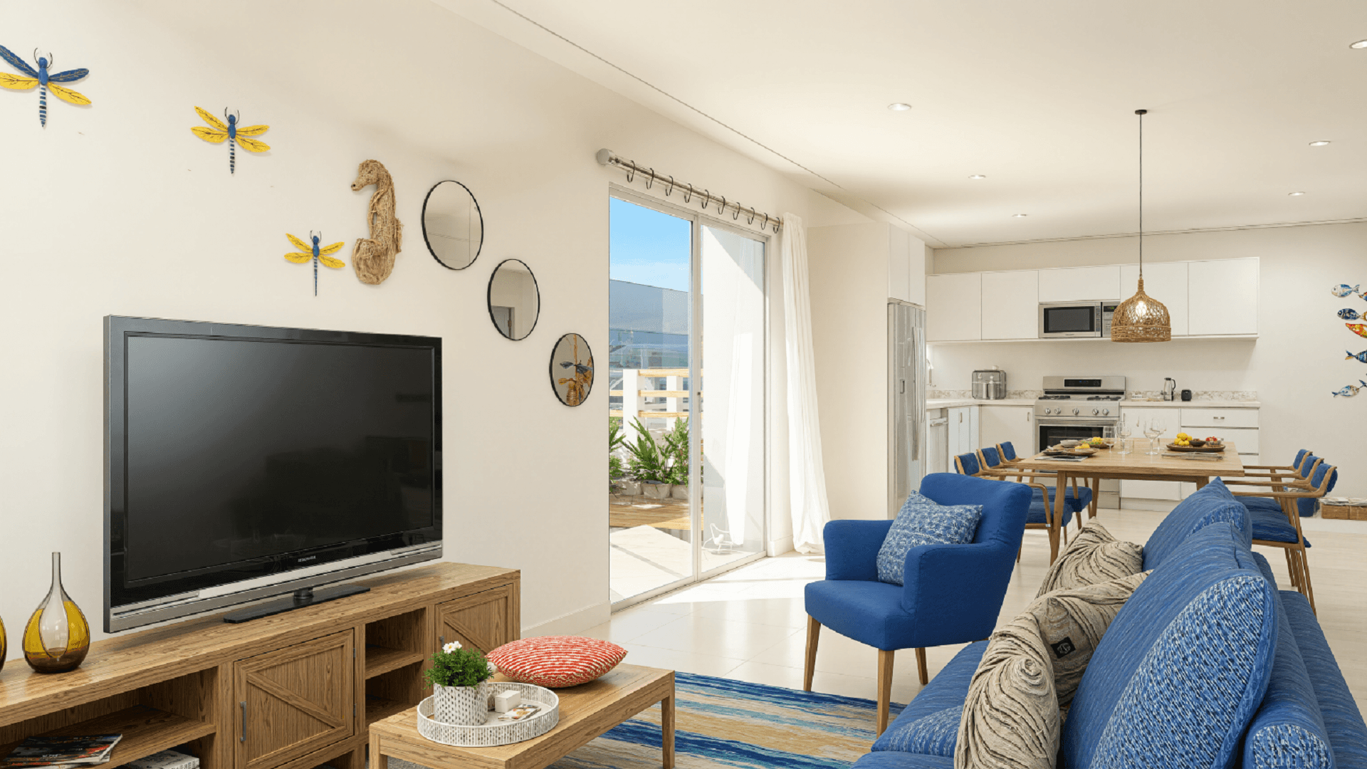 Living room and kitchen view inside Summerside III townhouse with blue seating, entertainment area, and open kitchen layout