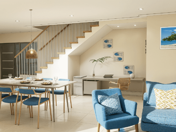 Open living and dining area inside Summerside III townhouse featuring staircase access, blue seating, and workspace under the stairs.