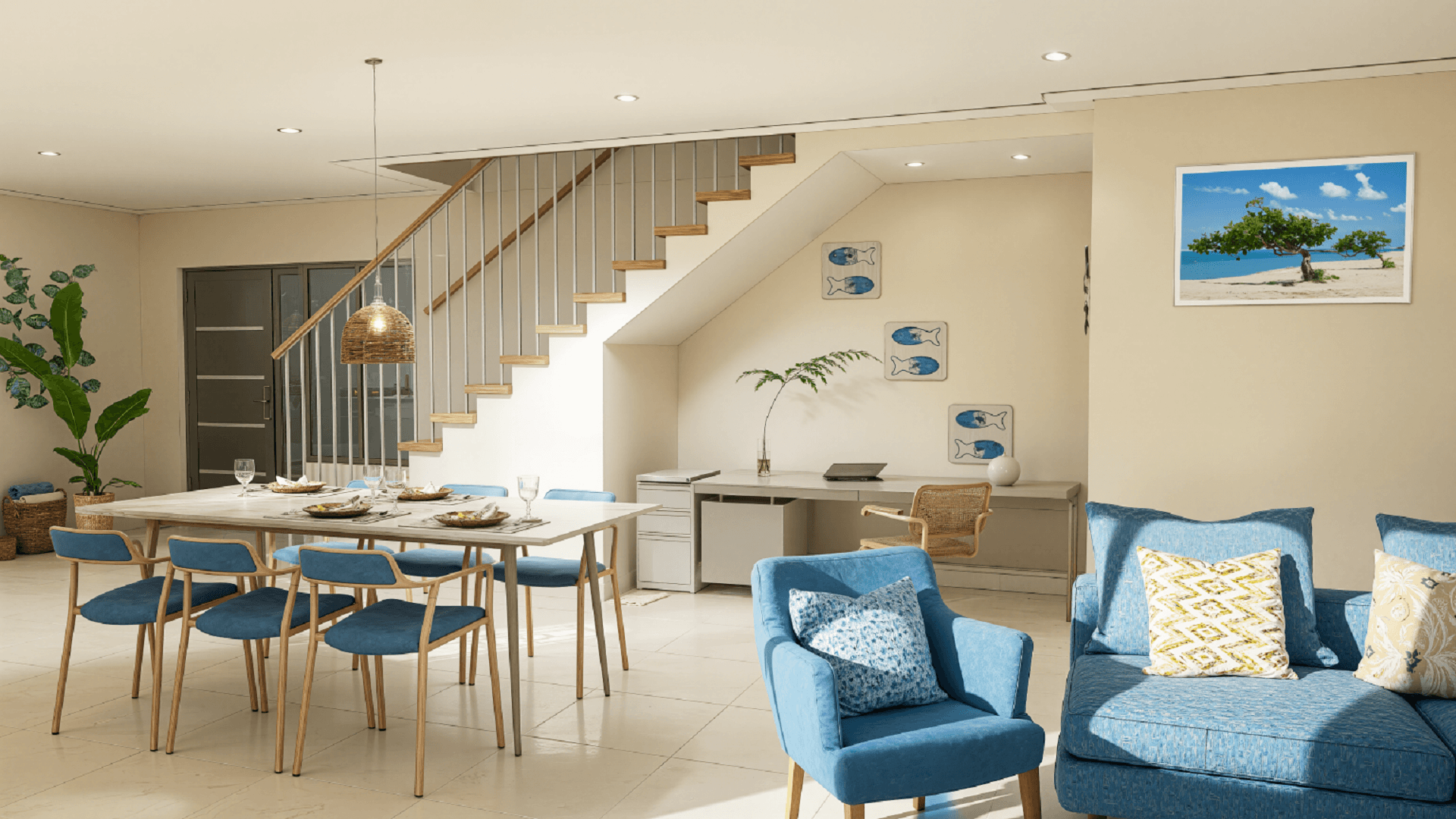 Open living and dining area inside Summerside III townhouse featuring staircase access, blue seating, and workspace under the stairs.